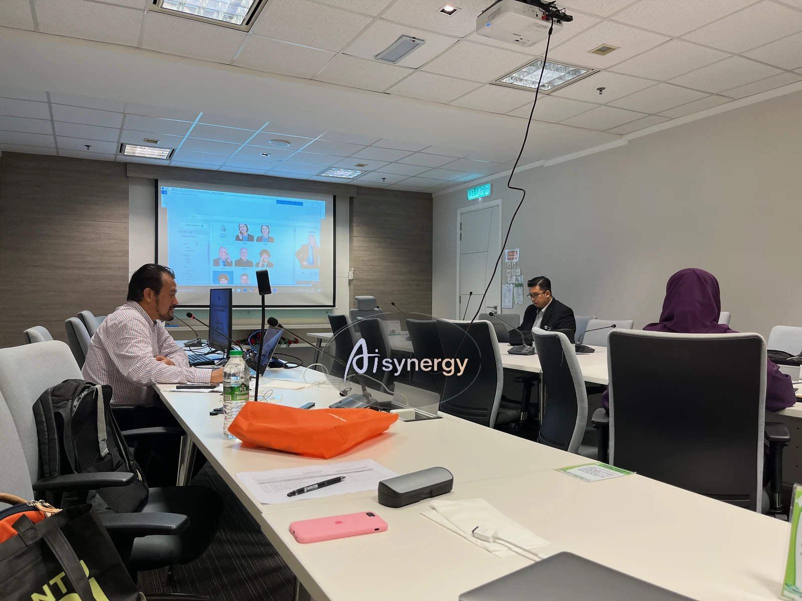 A boardroom-style training session viewed from another angle, with a presentation screen at the front